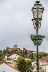 Fototapeta na wymiar View of a classic lamp post in Tomar city downtown, with Convent of Christ building as background