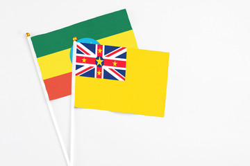 Niue and Ethiopia stick flags on white background. High quality fabric, miniature national flag. Peaceful global concept.White floor for copy space.