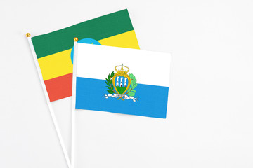 San Marino and Ethiopia stick flags on white background. High quality fabric, miniature national flag. Peaceful global concept.White floor for copy space.
