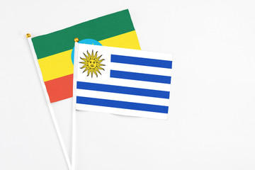 Uruguay and Ethiopia stick flags on white background. High quality fabric, miniature national flag. Peaceful global concept.White floor for copy space.