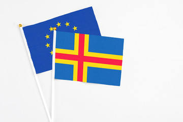 Aland Islands and European Union stick flags on white background. High quality fabric, miniature national flag. Peaceful global concept.White floor for copy space.