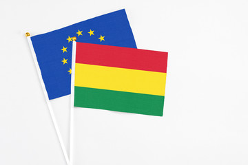 Bolivia and European Union stick flags on white background. High quality fabric, miniature national flag. Peaceful global concept.White floor for copy space.