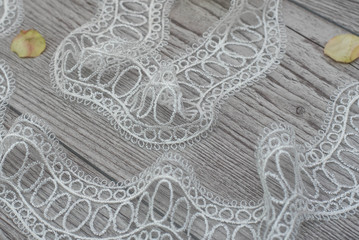 White wooden background with white spring flowers roses and lace ribbon. Happy womans day. The texture of lace on wooden background.