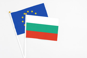 Bulgaria and European Union stick flags on white background. High quality fabric, miniature national flag. Peaceful global concept.White floor for copy space.