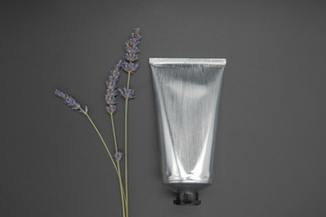 Lavender soothing cream tube and lavender flower, isolated on black background