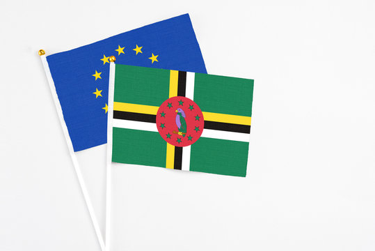 Dominica and European Union stick flags on white background. High quality fabric, miniature national flag. Peaceful global concept.White floor for copy space.