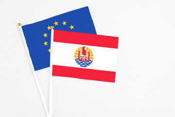 French Polynesia and European Union stick flags on white background. High quality fabric, miniature national flag. Peaceful global concept.White floor for copy space.