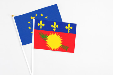 Guadeloupe and European Union stick flags on white background. High quality fabric, miniature national flag. Peaceful global concept.White floor for copy space.