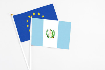 Guatemala and European Union stick flags on white background. High quality fabric, miniature national flag. Peaceful global concept.White floor for copy space.