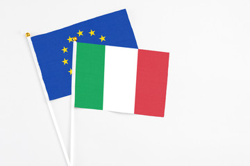 Italy and European Union stick flags on white background. High quality fabric, miniature national flag. Peaceful global concept.White floor for copy space.