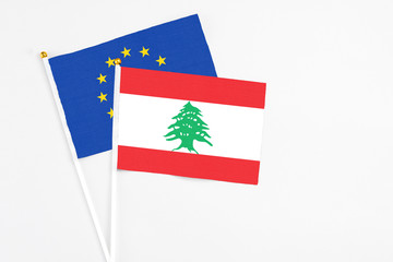 Lebanon and European Union stick flags on white background. High quality fabric, miniature national flag. Peaceful global concept.White floor for copy space.