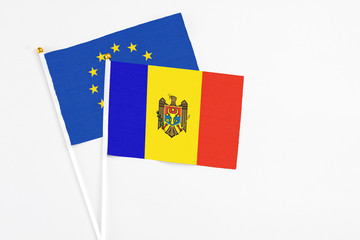 Moldova and European Union stick flags on white background. High quality fabric, miniature national flag. Peaceful global concept.White floor for copy space.