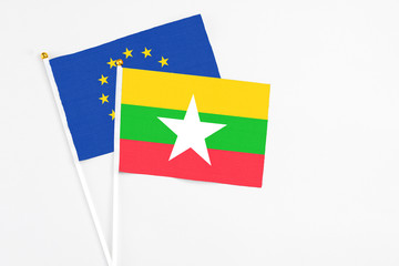 Myanmar and European Union stick flags on white background. High quality fabric, miniature national flag. Peaceful global concept.White floor for copy space.