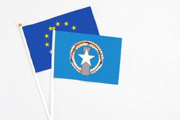 Northern Mariana Islands and European Union stick flags on white background. High quality fabric, miniature national flag. Peaceful global concept.White floor for copy space.
