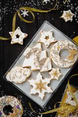 Gingerbread cookies gift set box with white icing, silver and golden sprinkles, snowflake, Christmas tree, stars and pig face on biscuits, dark wooden background, homemade sweets present, copy space 