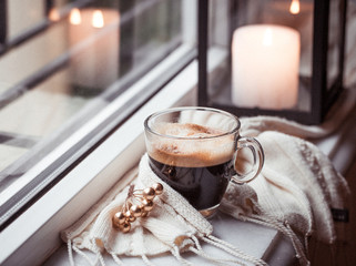 Glass cup of fresh strong americano coffee on marble windowsill in  winter morning with cinnamon...