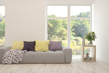 Fototapeta premium Stylish room in white color with sofa and summer landscape in window. Scandinavian interior design. 3D illustration
