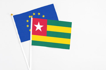 Togo and European Union stick flags on white background. High quality fabric, miniature national flag. Peaceful global concept.White floor for copy space.