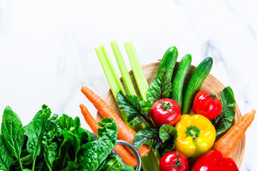 Mix of assorted fresh raw organic vegetables and greens in bowls for spring and summer dieting salad on white kitchen marble background. Healthy eating flat lay concept, copy space