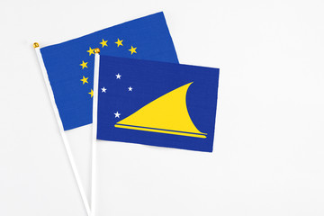 Tokelau and European Union stick flags on white background. High quality fabric, miniature national flag. Peaceful global concept.White floor for copy space.