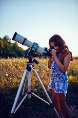 Little girl using telescope in nature to explore the universe.