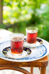 Two crystal glasses of black tea with saucers in garden, Novruz or Ramadan celebration, copy space