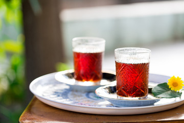Two crystal glasses of black tea with saucers in garden, Novruz or Ramadan celebration, copy space