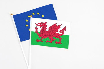 Wales and European Union stick flags on white background. High quality fabric, miniature national flag. Peaceful global concept.White floor for copy space.