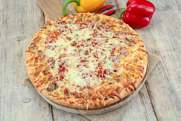 whole pizza with ham and mozzarella on a wooden table