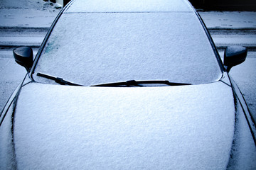 Frozen car covered snow at winter day, view front window windshield and hood.