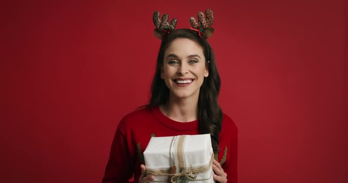 Woman with Christmas present on red background 