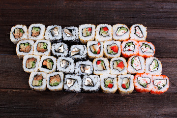 Fresh sushi roles on a wooden plate with hands of the chef in the background