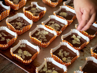 Motion blur spreading almonds sliced on homemade chocolate cupcakes on table.