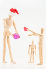 Concept image illustrating love and giving during the Christmas holiday season using wooden models isolated on a white background. 