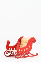 Model of a red coloured Santa sleigh isolated against a white background.