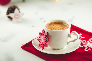 Cup of espresso or americano coffee in white cup in cosy Christmas arrangement, festive decoration with bokeh background, copy space