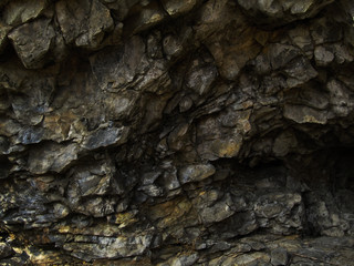 Dark rock texture. Stone background. Grunge stone background. The surface of the wall at the entrance to the cave. Mountain close-up.