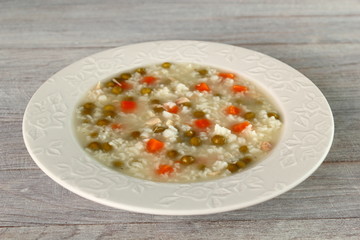 Rice soup with chicken, green peas and carrots