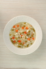 Rice soup with chicken, green peas and carrots. Directly Above.