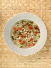 Rice soup with chicken, green peas and carrots. Directly Above.