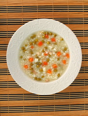 Rice soup with chicken, green peas and carrots. Directly Above.