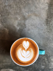 heart love and leaf latte art coffee in white and green cup on cement background with natural light , vintage style and copy space.