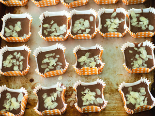 Motion blur spreading almonds sliced on homemade chocolate cupcakes on table.