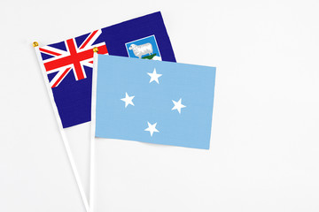 Fototapeta premium Micronesia and Falkland Islands stick flags on white background. High quality fabric, miniature national flag. Peaceful global concept.White floor for copy space.
