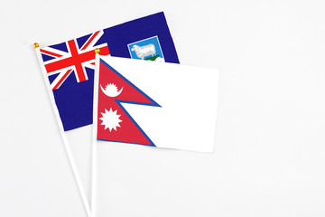 Fototapeta premium Nepal and Falkland Islands stick flags on white background. High quality fabric, miniature national flag. Peaceful global concept.White floor for copy space.
