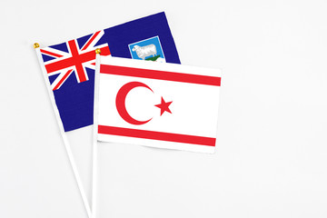 Fototapeta premium Northern Cyprus and Falkland Islands stick flags on white background. High quality fabric, miniature national flag. Peaceful global concept.White floor for copy space.