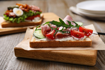 Fototapeta na wymiar Tasty sandwich with ham served on wooden table