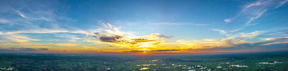 Panorama Top view Aerial photo from flying drone over village in Thailand.Cumulus sunset clouds with sun setting down on dark background.