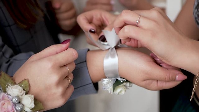 Few girls tie gray / silver ribbon on one of their arm. Concept wedding. Slow motion