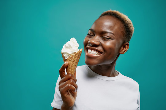 Cheerful female in white shirt and eating cold ice cream